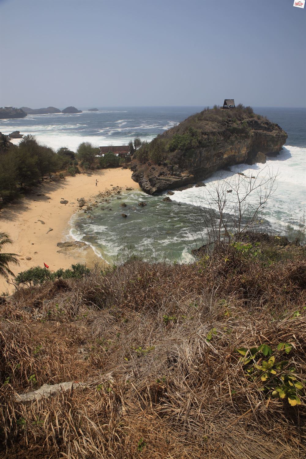 Looking down from the dry-grass hillside to Kasap Beach, its green lagoon and the rocky headland